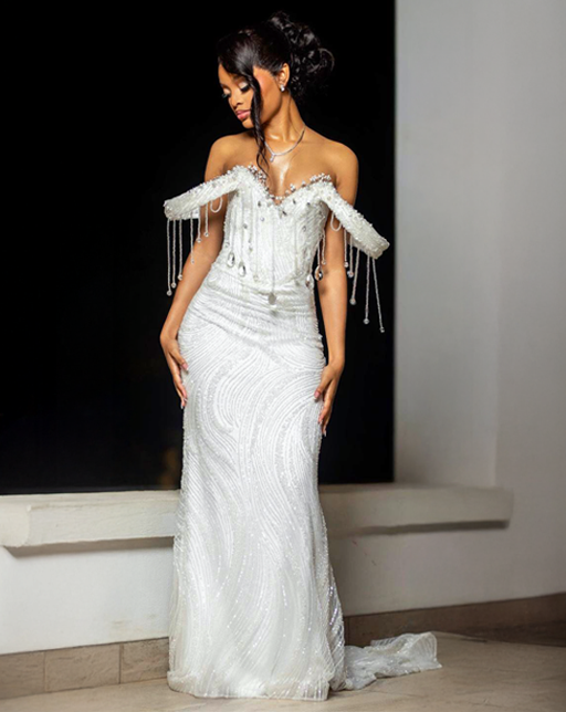 Custom white beaded lace and satin off-the-shoulder matric dance dress with crystal fringe detailing worn by a young woman.